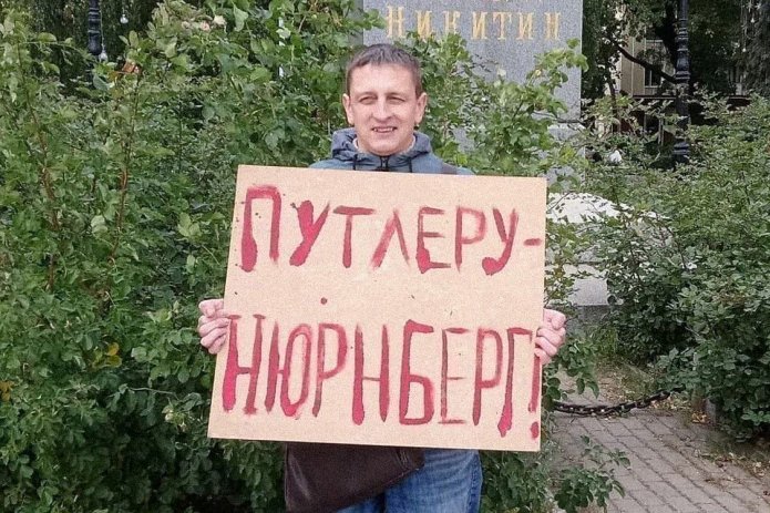 <em>Григорий Северин в одиночном пикете. За этот же плакат в январе 2021 года его <a href="https://fuqohnym---mekodxpr-bsccljbcrq-ez.a.run.app/express-news/2021/01/20/voronezhca-arestovali-iz-za-odinochnogo-piketa-v-podderzhku-navalnogo"><u>арестовали</u></a> на пять суток (ч. 8 ст. 20.2 КоАП РФ) / Фото: Свободные Люди Воронежа</em>